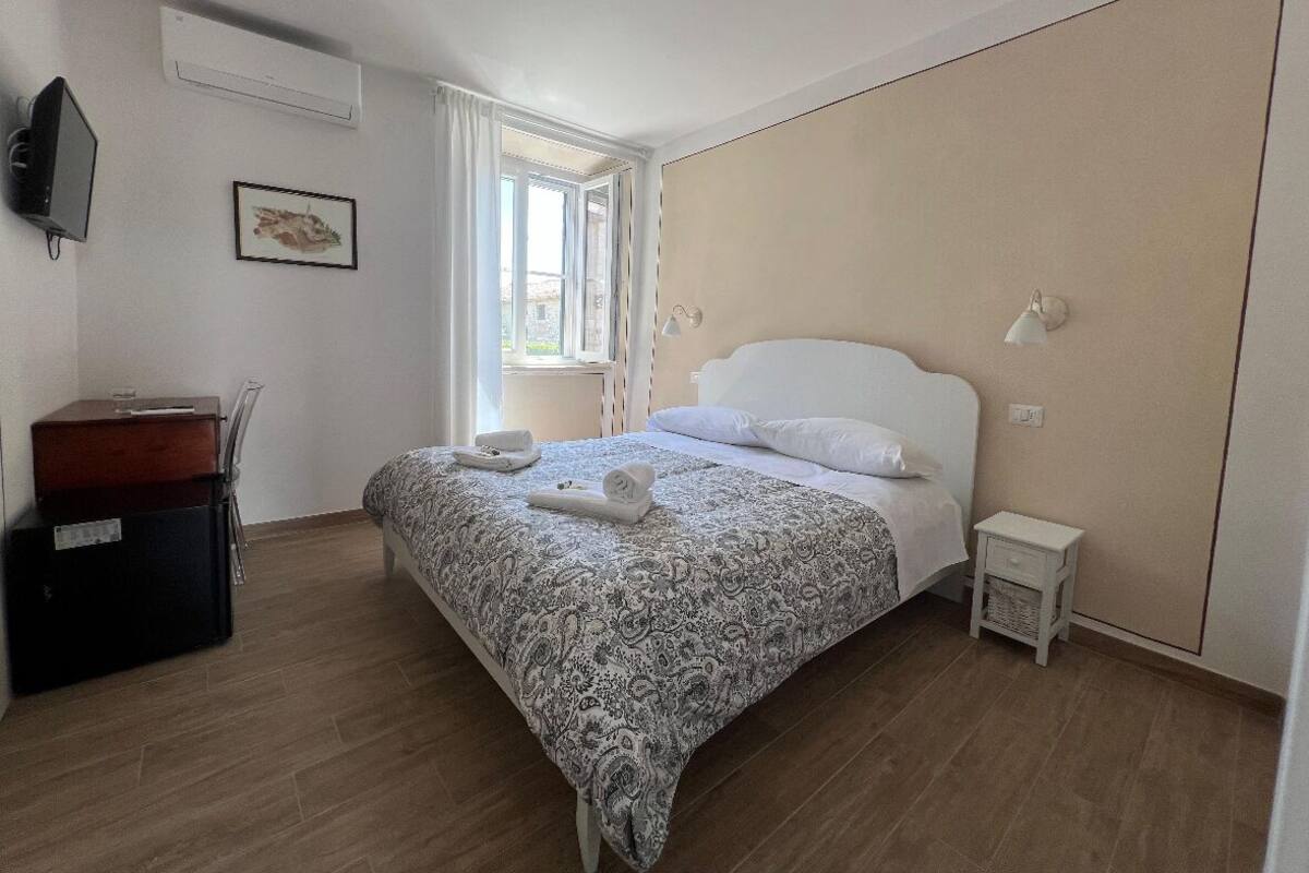 A neatly arranged bedroom with a bed, bedside table, and a desk with a chair.