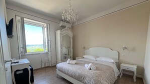 A bedroom with a bed, a desk, a chair, a dresser, and a chandelier. - Dimora dei Magi (Saturnia)