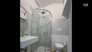 A bathroom with a glass-enclosed shower, a white sink, and a toilet. - Dimora dei Magi (Saturnia)