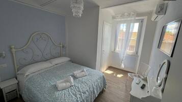 A bedroom with a bed, bedside table, and a bathroom with a sink and mirror.