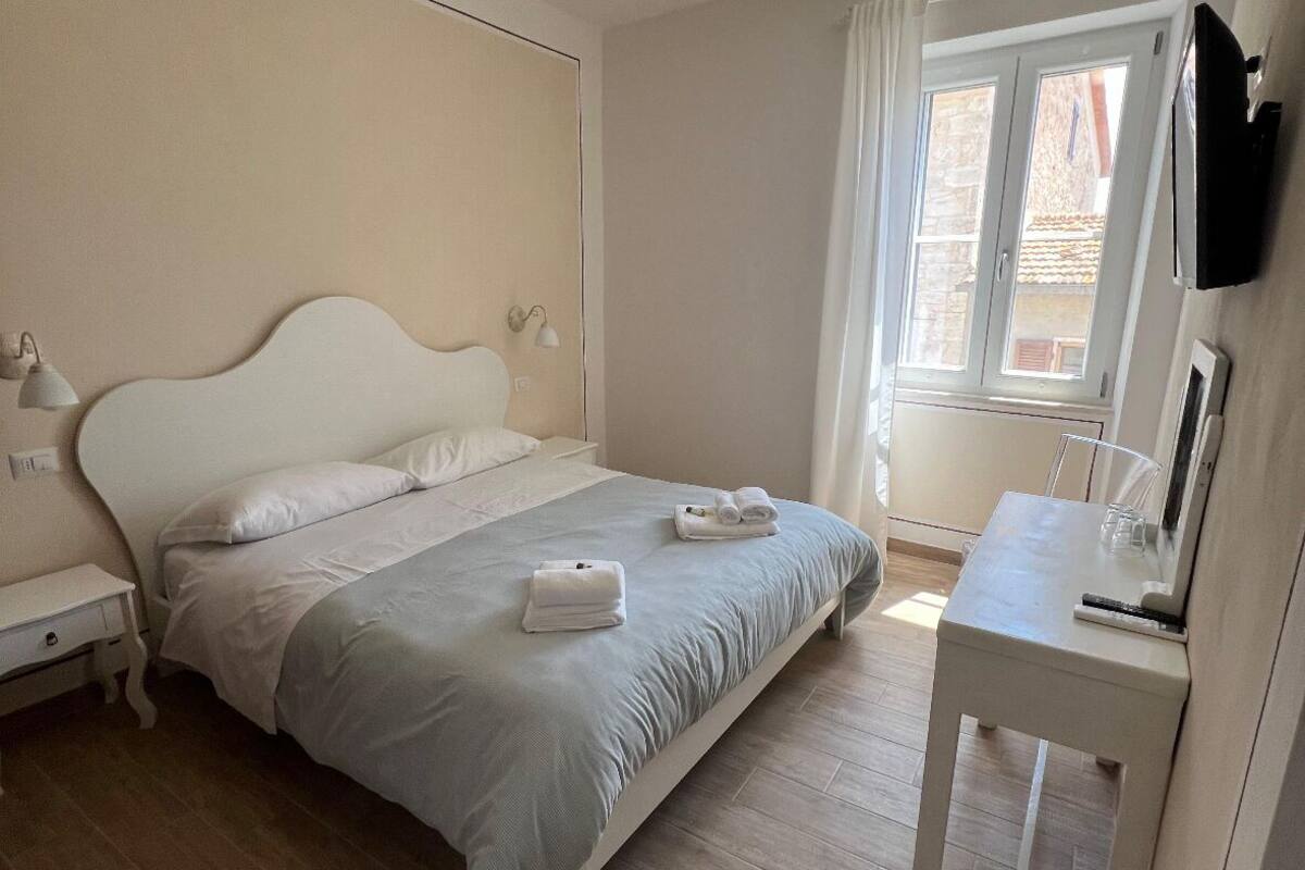 A bedroom with a bed, bedside table, and a window.