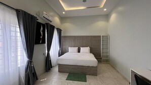 A modern hotel room with a large bed, a desk, and a built-in shelf.
