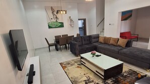 A modern living room with a sectional sofa, a coffee table, and a flat-screen TV on a white stand.