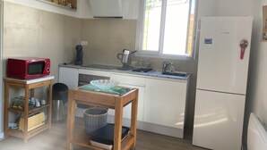 Une cuisine compacte équipée d’un four à micro-ondes, d’une machine à café, d’un évier et d’un réfrigérateur.