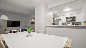 Uma cozinha moderna com armários brancos, micro-ondas e geladeira de aço inoxidável.
