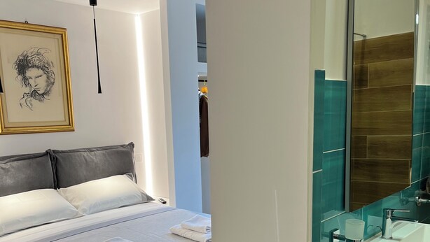 Een moderne slaapkamer met een groot bed, een nachtkastje en een wandlamp.