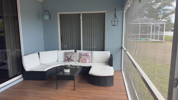 Ett takförsett utomhusområde med sittplatser, bestående av en modulsoffa, ett litet bord och en krukväxt.
