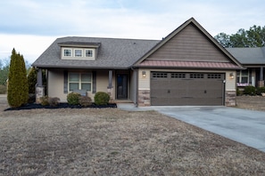 A two-story house with a garage, a small porch, and a well-maintained lawn.
