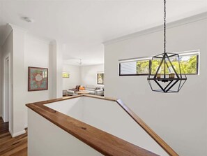 Ein modernes Interieur mit einer Holztreppe, einer hängenden Leuchte und Blick durch ein Fenster.