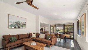 Un salon moderne avec un canapé d’angle, une table basse en bois et un ventilateur de plafond.
