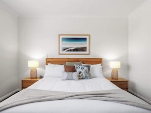 A neatly made bed with white linens, a wooden headboard, and two bedside lamps. - Trailside Vista—Modern Comfort near Geographe Bay (Dunsborough)