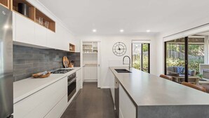 Une cuisine moderne avec des meubles blancs, un réfrigérateur en acier inoxydable et un grand îlot central doté d’un évier.