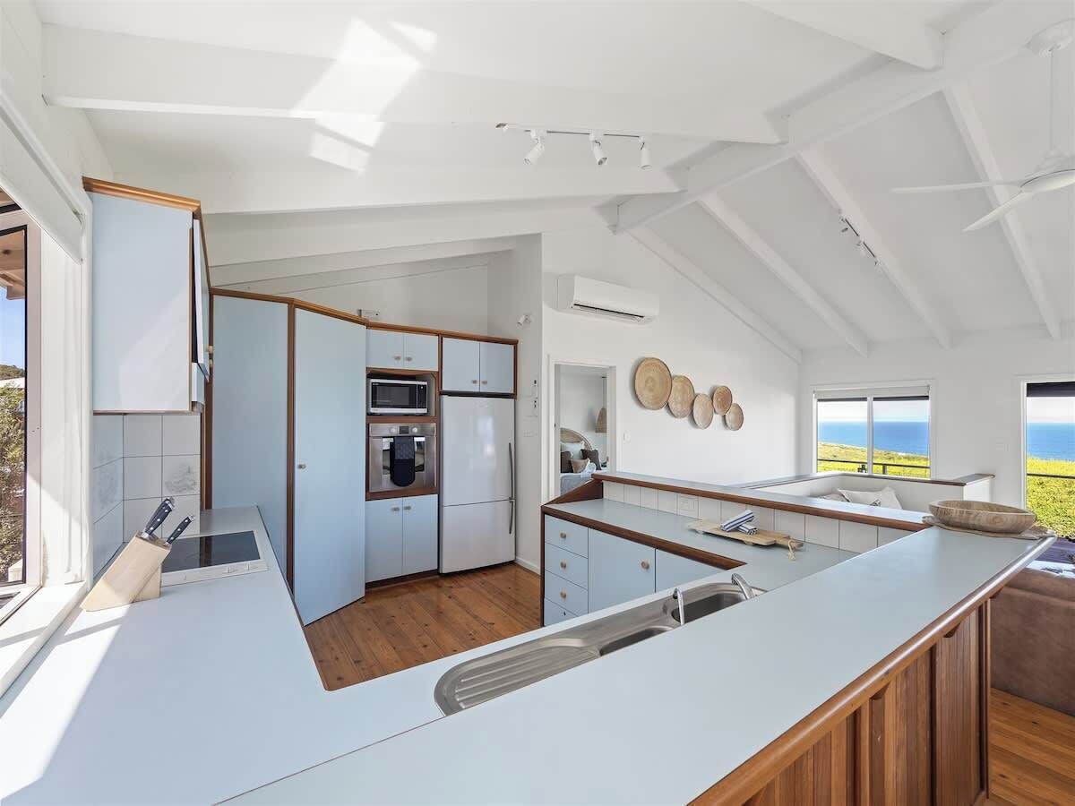 A modern kitchen with a large island, built-in appliances, and a view of the ocean.