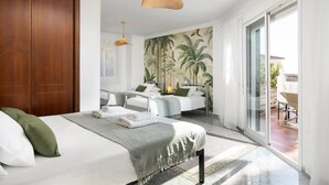 A hotel room with a large bed, a sitting area with a table, and a sliding glass door leading to an outdoor patio. - Villa Selvatic with Sea Views, Pool, Sauna, and Cinema (Arenas)
