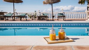 A poolside area with lounge chairs, umbrellas, and two drinks on a tray. - Villa Selvatic with Sea Views, Pool, Sauna, and Cinema (Arenas)