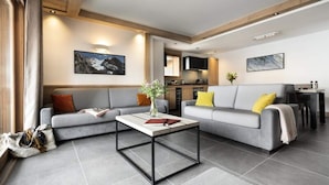 Una sala de estar moderna con un sofá gris, una mesa de centro y una cocina al fondo.