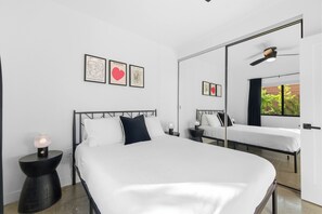 A modern bedroom with a large bed, a bedside table with a lamp, a mirror, and artwork on the wall. - Private yard|AC|EV| Relocation| Remote work (San Diego)