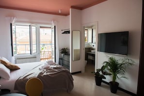 A bedroom with a bed, a TV, a mirror, and potted plants. - Le Terrazze del Duca (Rome)