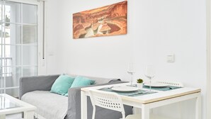 Ein Essbereich mit einem Tisch für zwei Personen, einem weißen Stuhl und einem Weinglas auf dem Tisch.