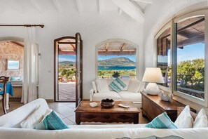 A spacious living room with a sofa, coffee table, and a view of the sea. - Villa Lo Scoglietto, Costa Corallina, Sea View, Private Terrace, Air Conditioning (Costa Corallina)