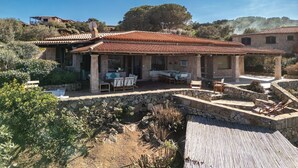 Une villa de style méditerranéen, dotée d’un toit en tuiles, d’un espace extérieur aménagé et de murs en pierre.
