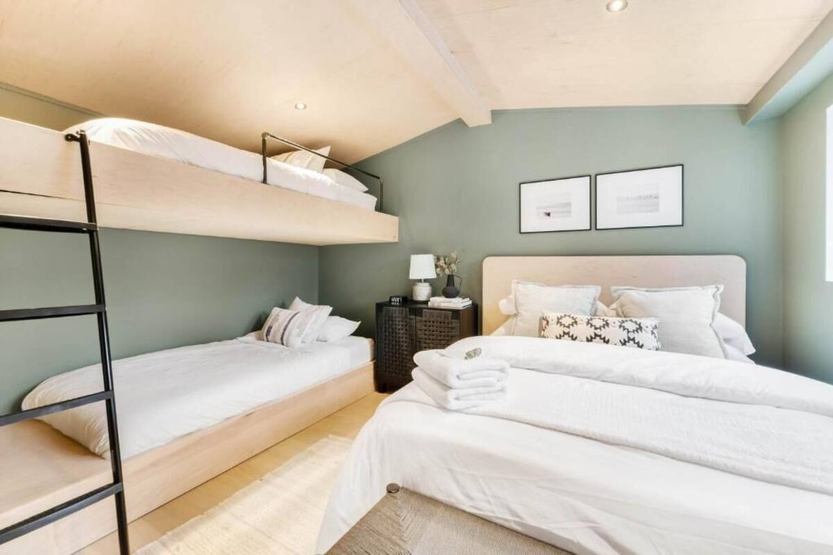 Un dormitorio con literas, una mesita de noche con lámpara y cuadros en la pared.
