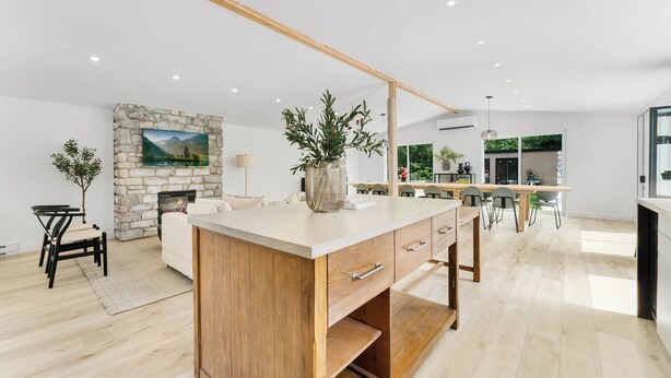 Una cucina moderna con isola centrale, camino in pietra e zona pranzo con sedie.