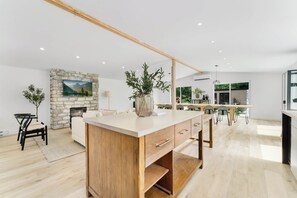 A modern kitchen with a central island, a stone fireplace, and a dining area with chairs. - Rockway Motel  (Amherst)
