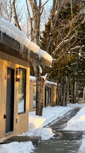 A row of wooden cabins with snow-covered roofs and a pathway leading through them. - Rockway Motel  (Amherst)