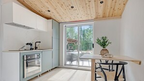 Una cucina moderna con una grande finestra, soffitto in legno e zona pranzo con tavolo e sedie.