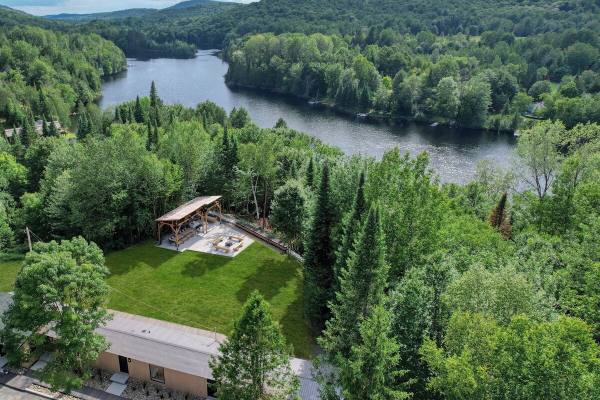 A riverside property with a gazebo, a lawn, and dense forest.