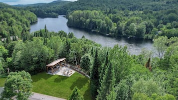 En ejendom ved floden med en pavillon, græsplæne og tæt skov.
