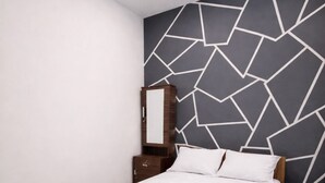 Ein modernes Hotelzimmer mit einem großen Bett, einem Nachttisch, einem Spiegel und einer Wand mit geometrischem Muster.
