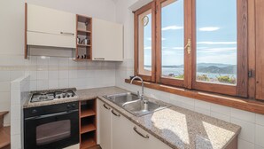 Une cuisine équipée d’une cuisinière, d’un four, d’un évier et de meubles de rangement en bois.