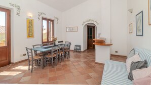 Un coin repas avec une table et des chaises en bois, un petit comptoir de cuisine et un canapé à rayures.