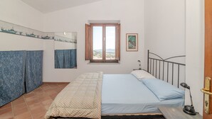 Une chambre à coucher avec un lit, une fenêtre, un miroir et une porte.