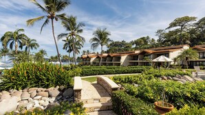 Resort com piscina, palmeiras e um edifício com várias sacadas.