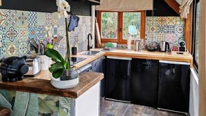 Een moderne keuken met een centraal eiland, zwarte apparaten en een kleurrijke tegelachtergrond.