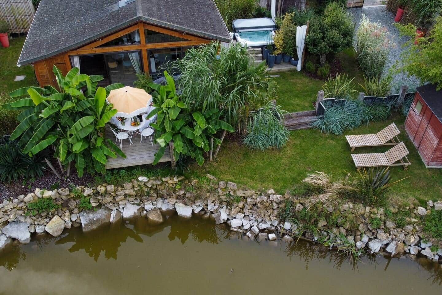 Una casa con una vasca idromassaggio, un patio con sedie e uno stagno.