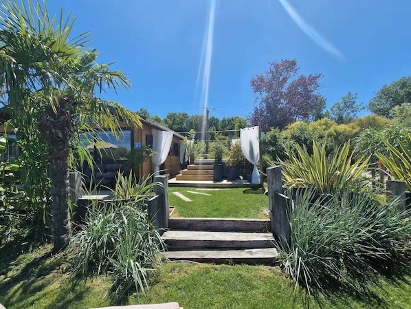 A garden pathway leading to a house with a clear sky.