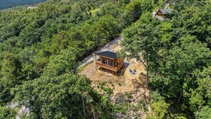 A wooden cabin with a balcony, surrounded by dense forest and mountains in the background. - Great place for One or Two, Cozy, Hot Tub, Views (Pigeon Forge)