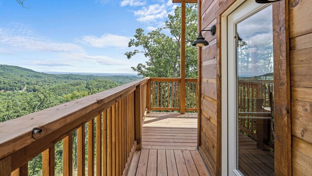A wooden deck with a glass door leading to a balcony with a scenic view of a forested landscape. - Great place for One or Two, Cozy, Hot Tub, Views (Pigeon Forge)