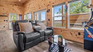 A cozy cabin interior with a leather sofa, large windows, and a retro arcade machine. - Great place for One or Two, Cozy, Hot Tub, Views (Pigeon Forge)