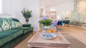 Ein modernes Wohnzimmer mit einem grünen Sofa, einem Holztisch mit dekorativer Platte und einer Vase mit Blumen.