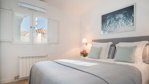 Ein Schlafzimmer mit einem Bett, einem Heizkörper, einem Fenster und einer Wandlampe.