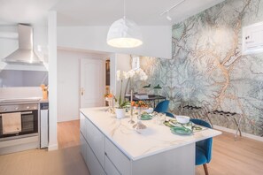 A modern kitchen with a marble island, a dining area with a blue chair, and a wall with a map design. - Charming Apartment with Terrace in Salamanca (Madrid)