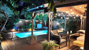 A wooden deck with a pool, outdoor furniture, and string lights. - Spacious 3BR Home w/ Heated Pool in the Heart of New Orleans (New Orleans)