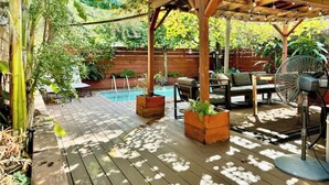 A wooden deck with a pool, outdoor furniture, and planters. - Spacious 3BR Home w/ Heated Pool in the Heart of New Orleans (New Orleans)