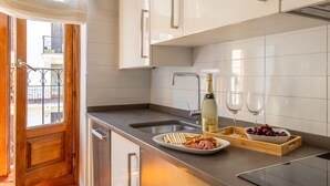 A modern kitchen with white cabinets, a stainless steel sink, and a wooden countertop. There is a bottle of champagne and two glasses on the counter. - Cozy Apartment for Two in Alcalá Area (Madrid)