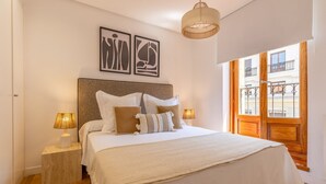 A bedroom with a large bed, two bedside lamps, a headboard, and artwork on the wall. - Cozy Apartment for Two in Alcalá Area (Madrid)